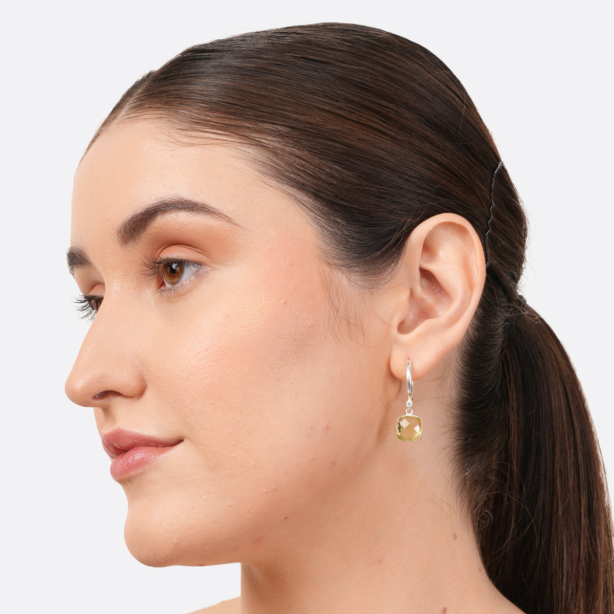 Side-profile portrait of a model wearing a RILAVE Lemon Quartz drop hoop earring with a pale yellow cushion-cut gemstone.