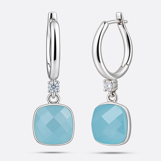 A pair of sterling silver drop hoop earrings featuring vibrant sky blue topaz stones and subtle clear crystal accents.