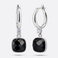 Front and angled views of the silver drop hoop earrings, showing the faceted garnet drops and the hinged fastening.