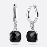 Front and angled views of the silver drop hoop earrings, showing the faceted garnet drops and the hinged fastening.