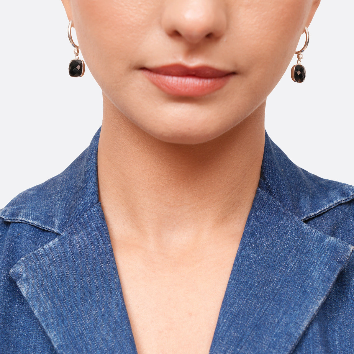 Front view of a model wearing both sterling silver drop hoop earrings, each finished with a faceted black garnet drop.