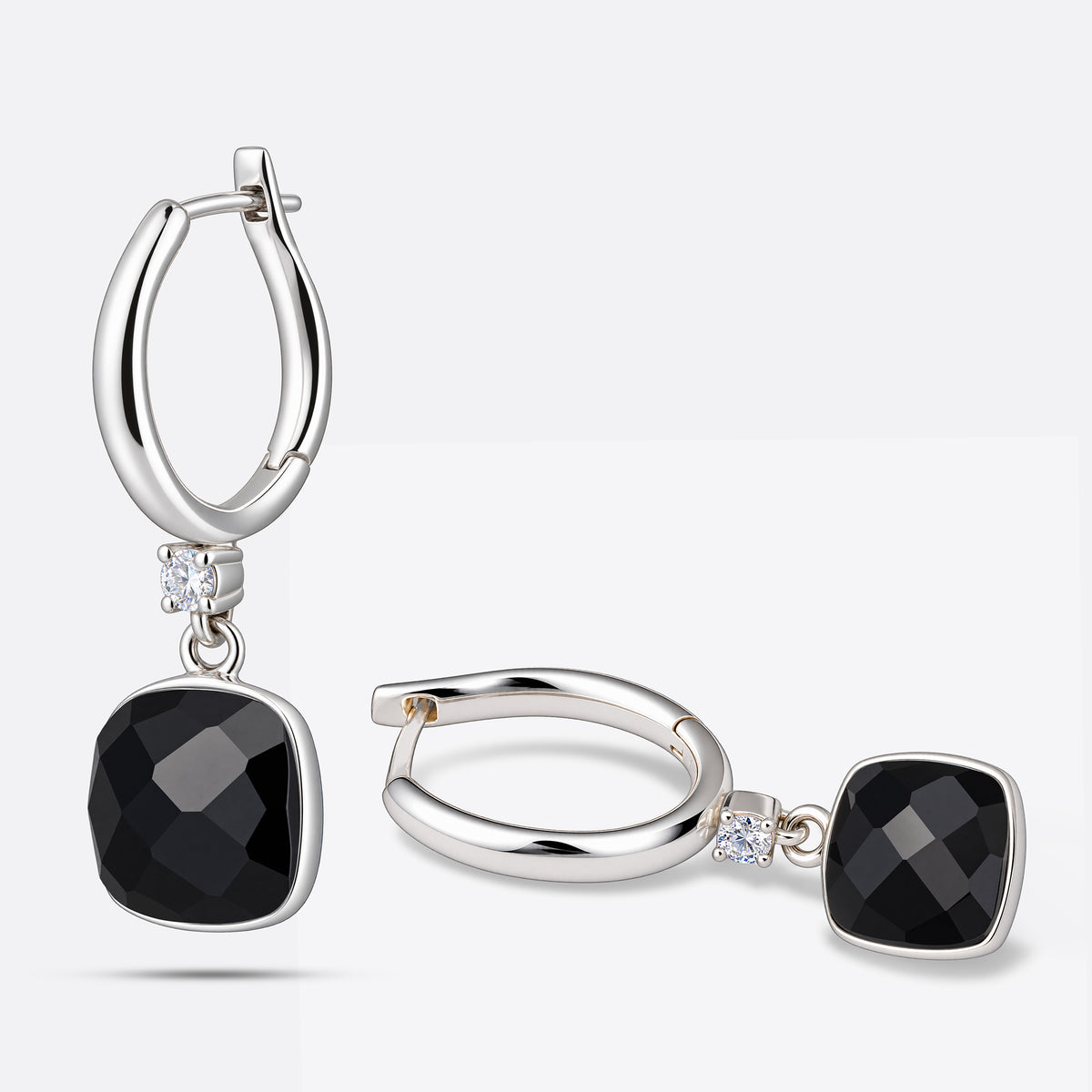 One drop hoop earring upright and the other laid flat, showing the polished silver hoops and faceted black garnet drops.