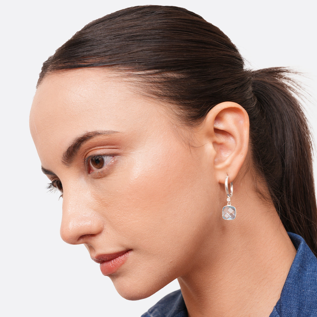 Model wearing a sterling silver drop hoop earring with a pale blue aqua chalcedony drop, seen from a three-quarter angle.