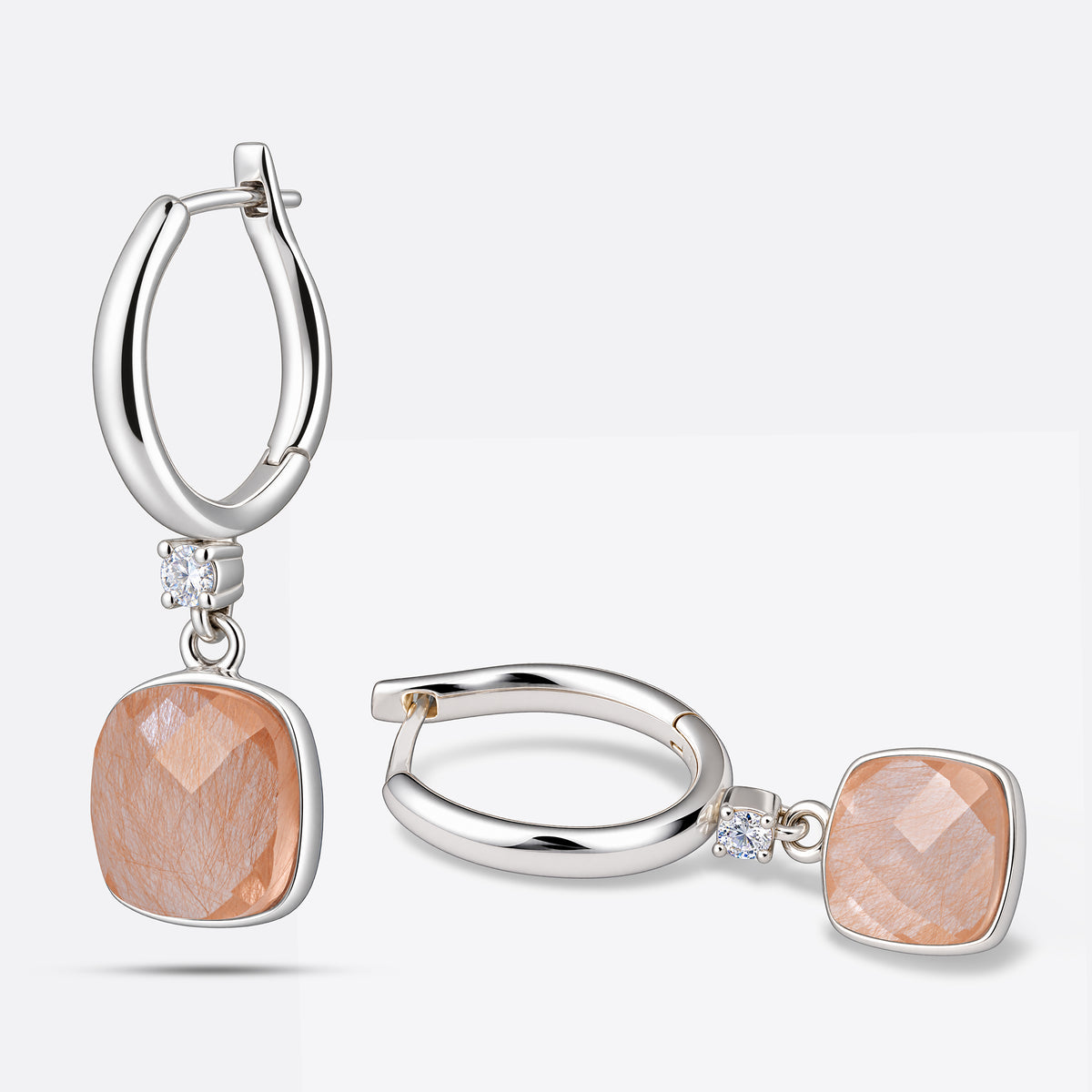 Pair of golden rutilated quartz drop hoop earrings in sterling silver, one upright and one resting on its side.
