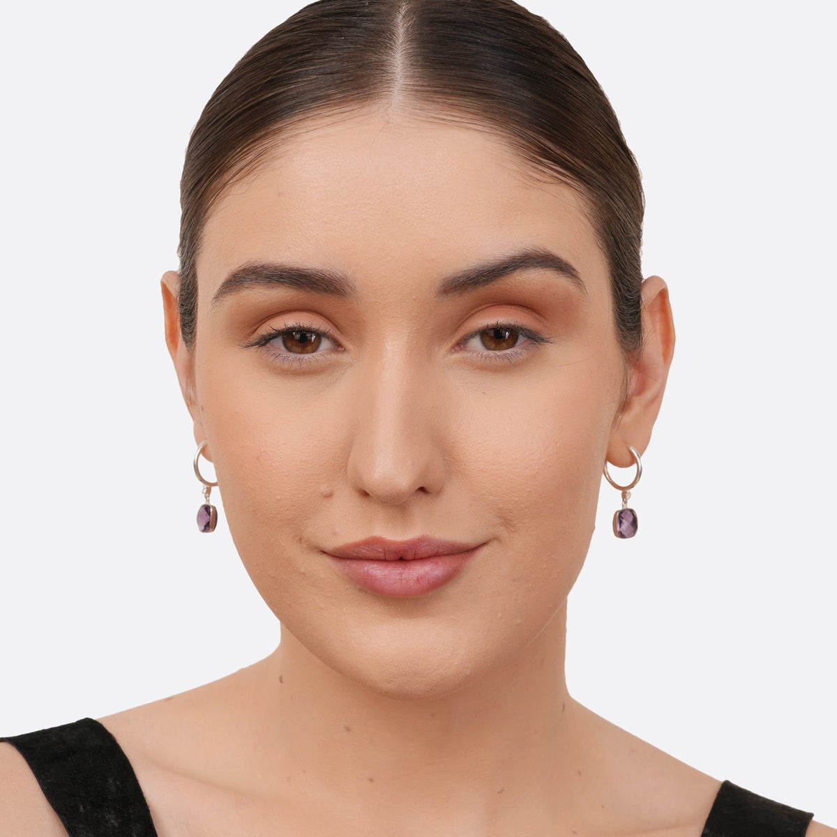 A model facing forward wearing RILAVE sterling silver drop hoop earrings featuring square-cut violet amethyst gemstones.