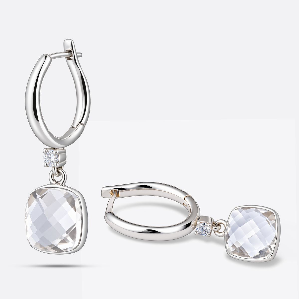 White Topaz drop hoop earrings presented against a white background, with one upright and the other resting flat to show depth.