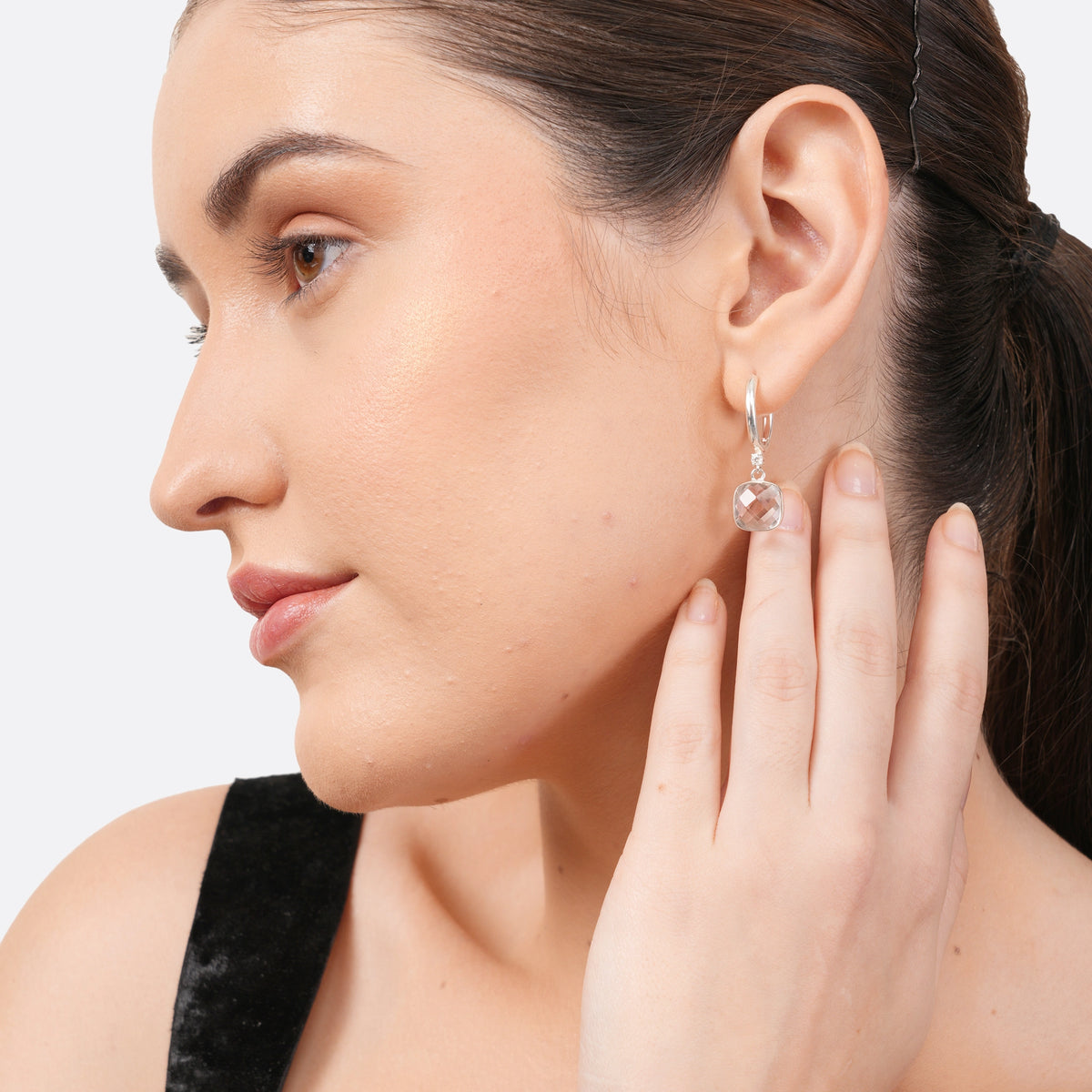 Model in profile wearing RILAVE silver drop hoop earrings, featuring a faceted White Topaz gemstone catching the light.
