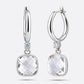 Sterling silver drop hoop earrings featuring a brilliant White Topaz, shown from straight and slightly angled front perspectives.
