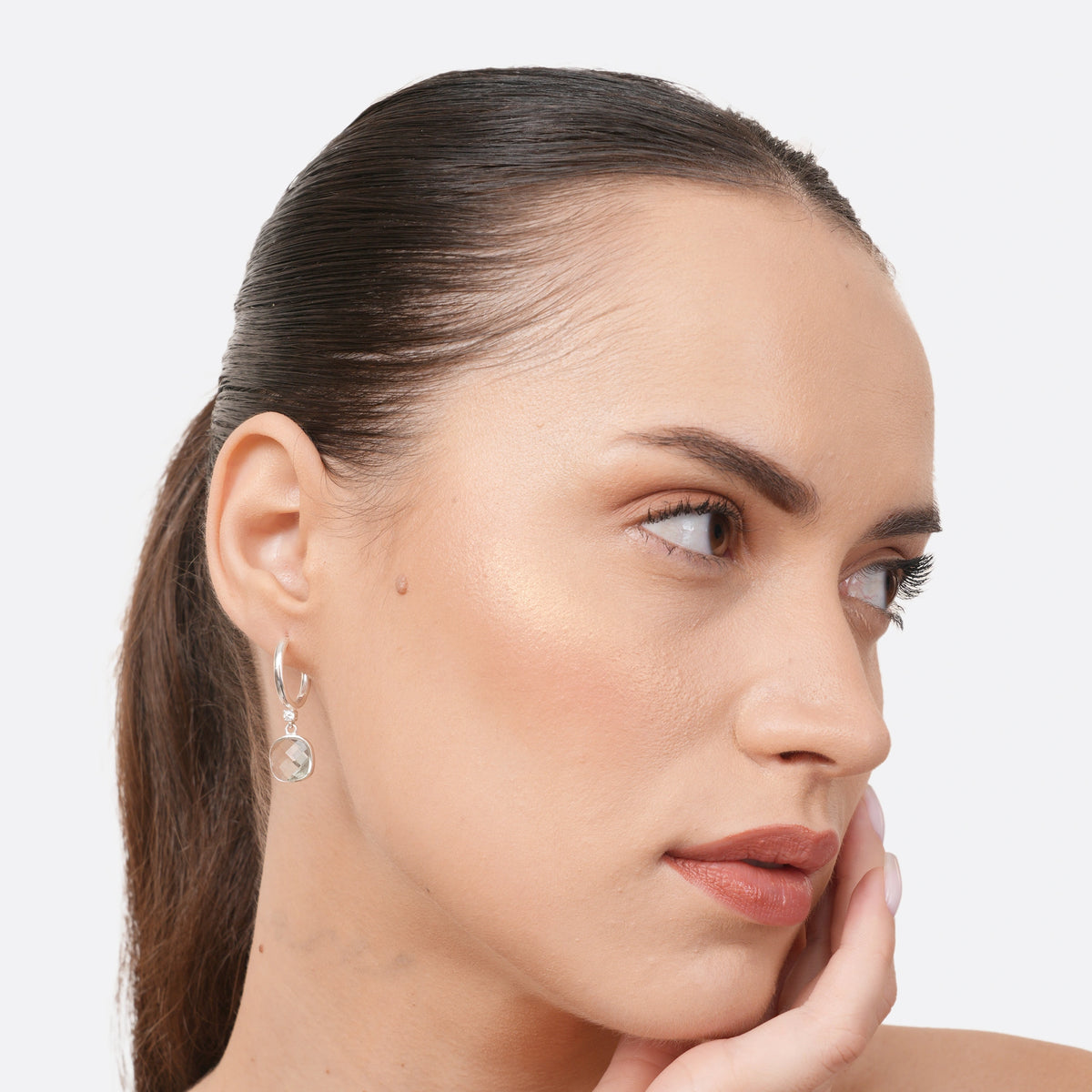 Three-quarter portrait of a model wearing a Green Amethyst drop hoop earring, showing the pale green stone and polished silver hoop.