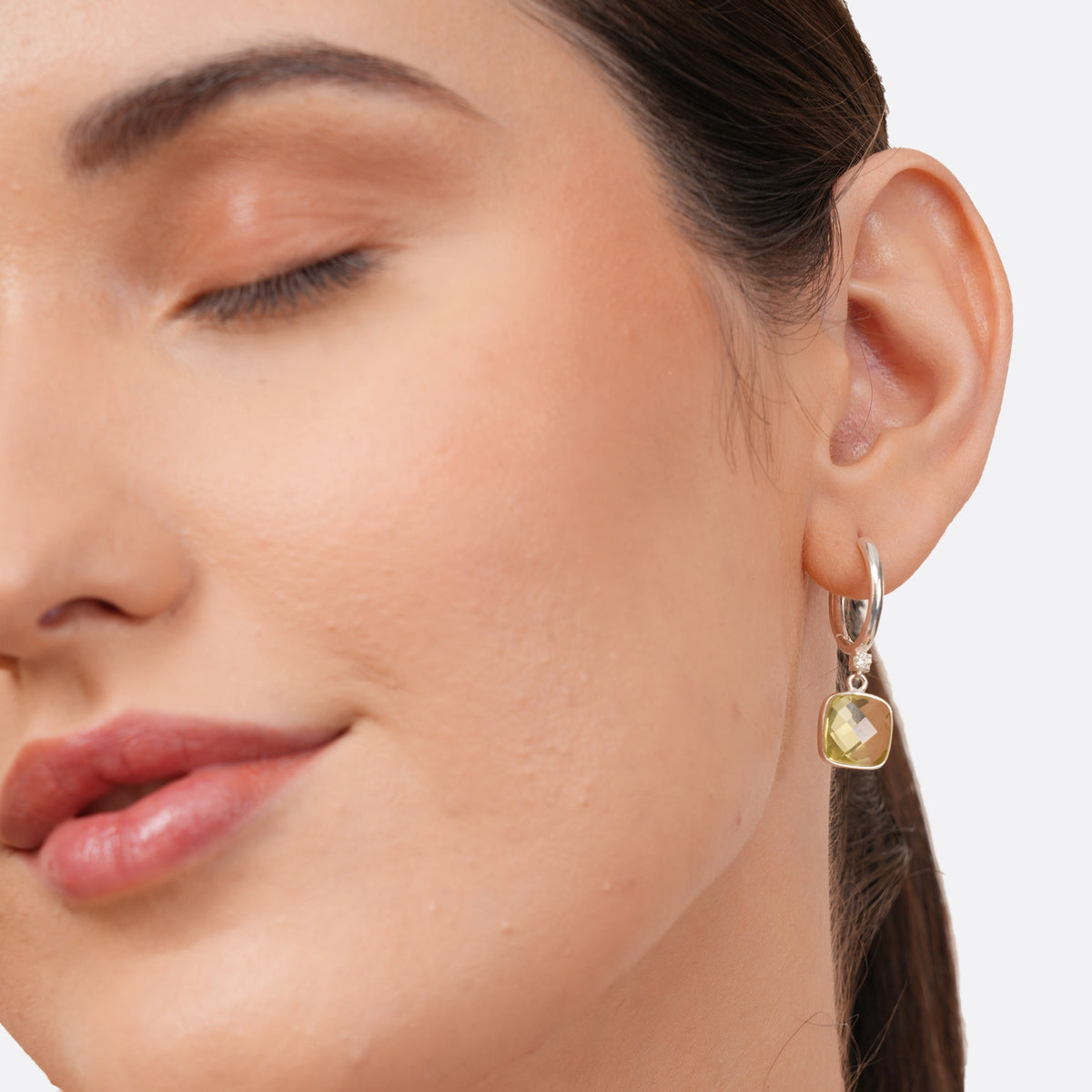 Close-up of a model wearing a Lemon Quartz drop hoop earring, highlighting the cushion-cut yellow stone suspended below the silver hoop.