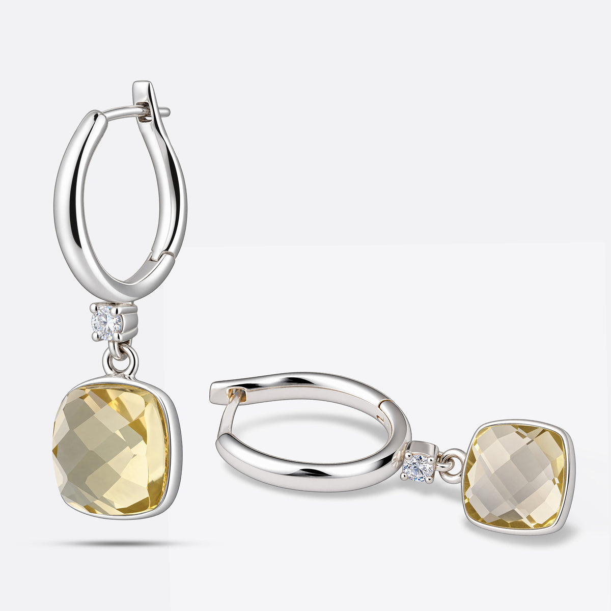 A pair of sterling silver Lemon Quartz drop hoop earrings, one upright and one laid flat, with cushion-cut yellow gemstones.