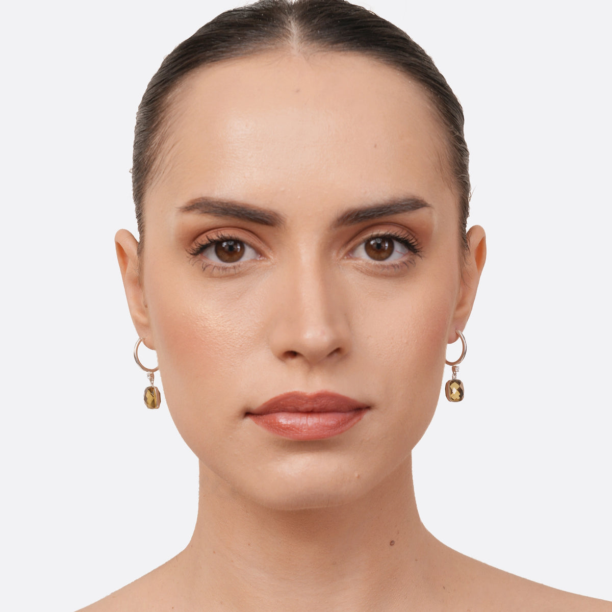 Model wearing RILAVE Olive Quartz drop hoop earrings, with faceted golden-brown gemstones suspended from silver hoops.