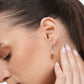 Close-up of a model wearing a sterling silver Olive Quartz drop hoop earring, viewed from the side with her hand raised.