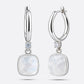 RILAVE Rainbow Moonstone drop hoop earrings in sterling silver, showing faceted cushion-shaped stones and an open hinged hoop.