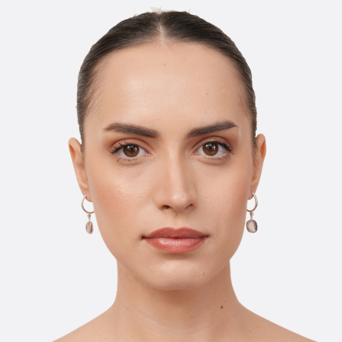 Model facing forwards wearing RILAVE Rose Quartz drop hoop earrings, with pale pink gemstones suspended beneath silver hoops.