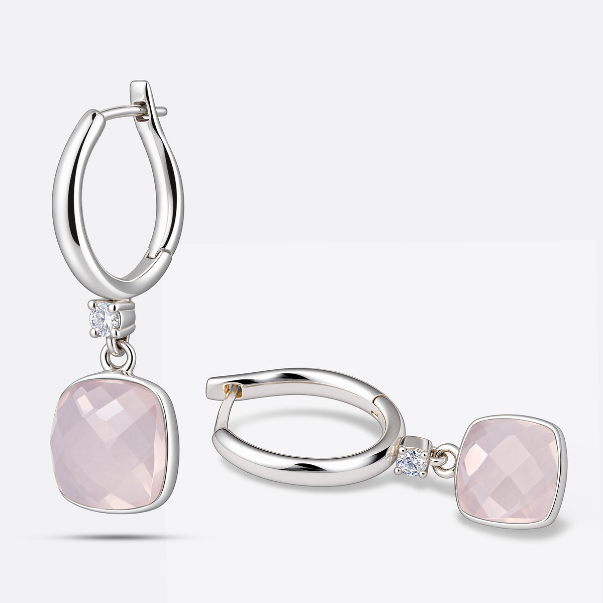 Pair of RILAVE Rose Quartz drop hoop earrings arranged upright and sideways, showing pale pink gemstones and polished silver hoops.